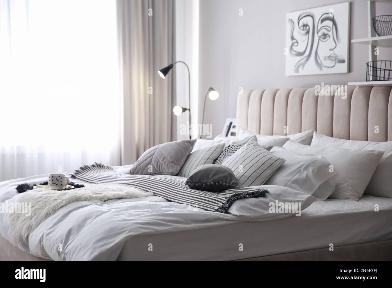 Acogedor dormitorio con cama grande, cojines decorativos y paredes a rayas  en blanco y azul Fotografía de stock - Alamy