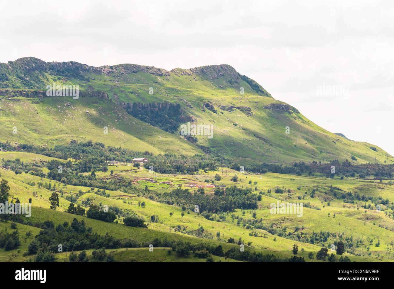 Paisaje de montaña Drakensberg primer plano con pueblo africano rural en la ladera en la temporada de verano verde en Kwazulu Natal, Sudáfrica Foto de stock