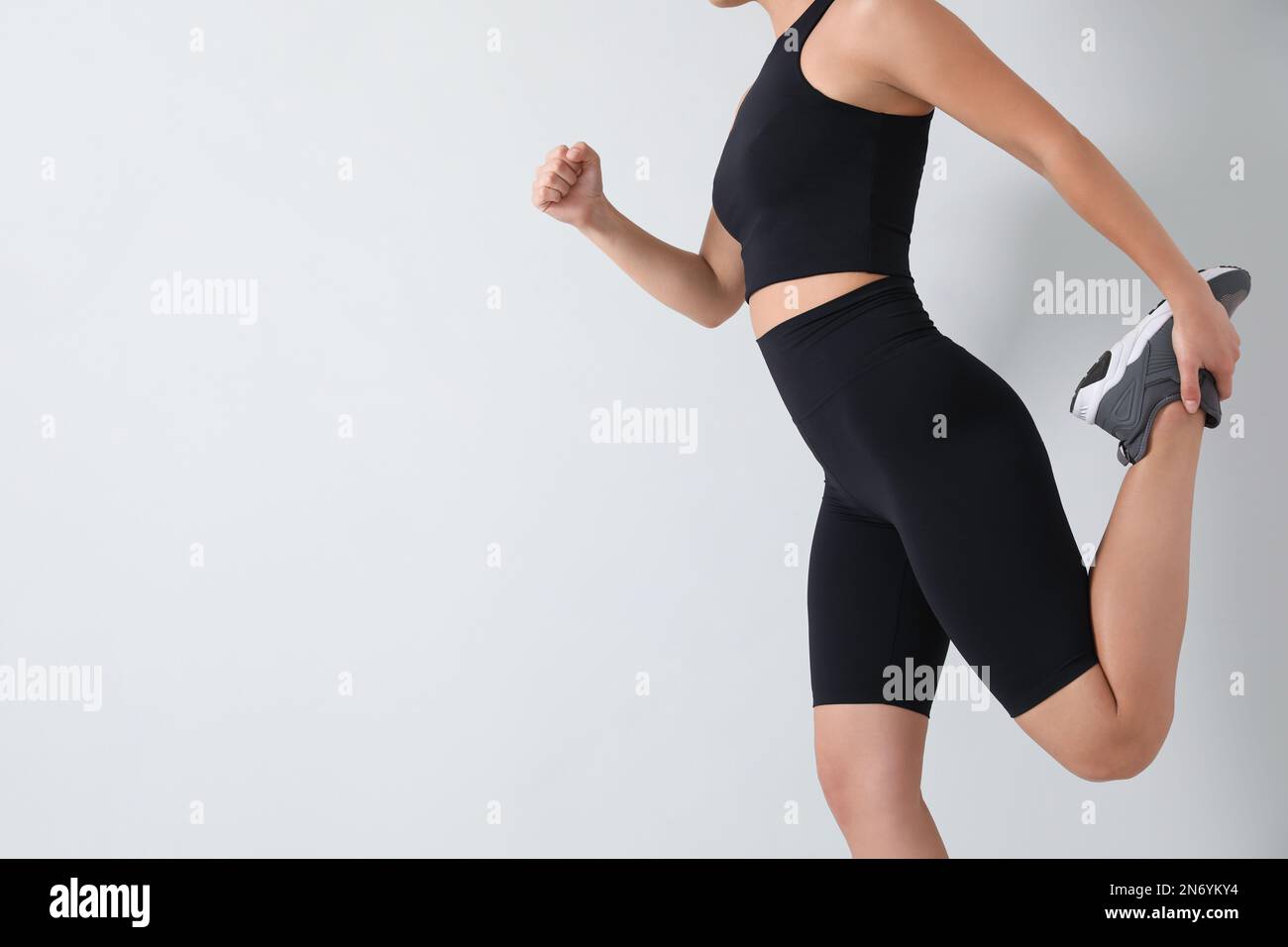 Mujer joven con ropa deportiva negra cerca de la pared de luz, primer  plano. Espacio para texto Fotografía de stock - Alamy