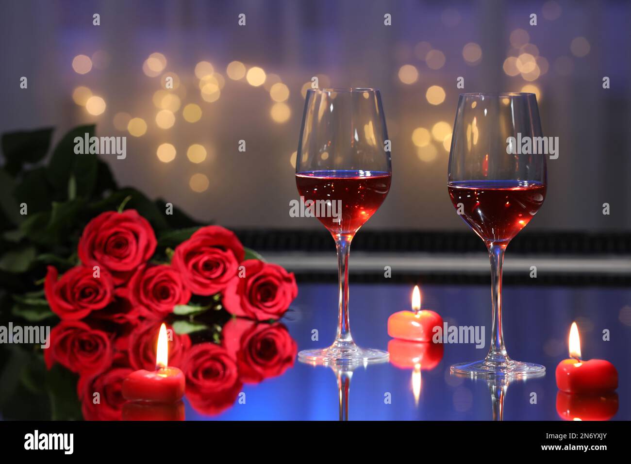 Copas de vino, velas y rosas en la mesa contra luces borrosas. Cena  romántica para el día de San Valentín Fotografía de stock - Alamy
