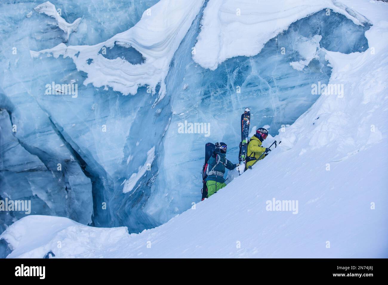 Dos snowboarders y esquiadores profesionales exploran y esquían una grieta / cueva de hielo en lo alto del glaciar Pitztal, Pitztal, Tirol, Austria Foto de stock
