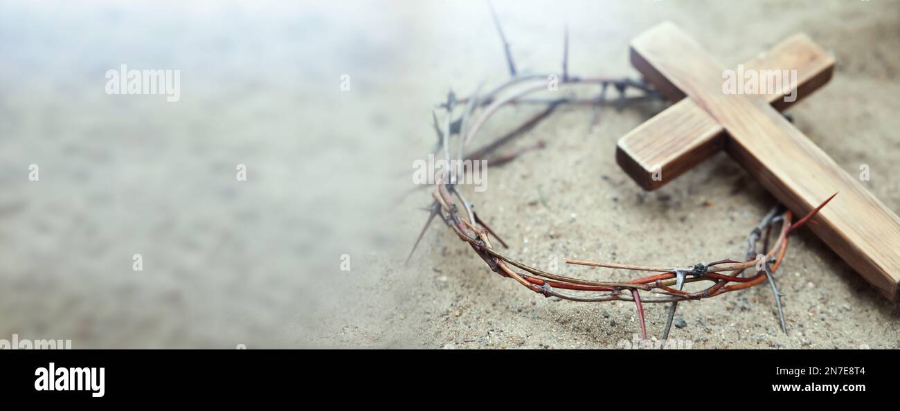 Pasión de Jesucristo. Corona de espinas y cruz de madera sobre arena, diseño de banner Foto de stock