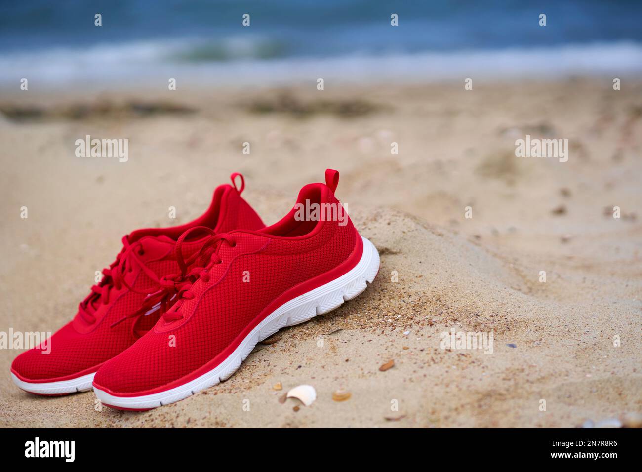 amanecer Ejercicio mañanero lengua Zapatos rojos de las señoras en la playa de arena vacía. 1 par de zapatillas  deportivas y de ocio. Calzado Fotografía de stock - Alamy