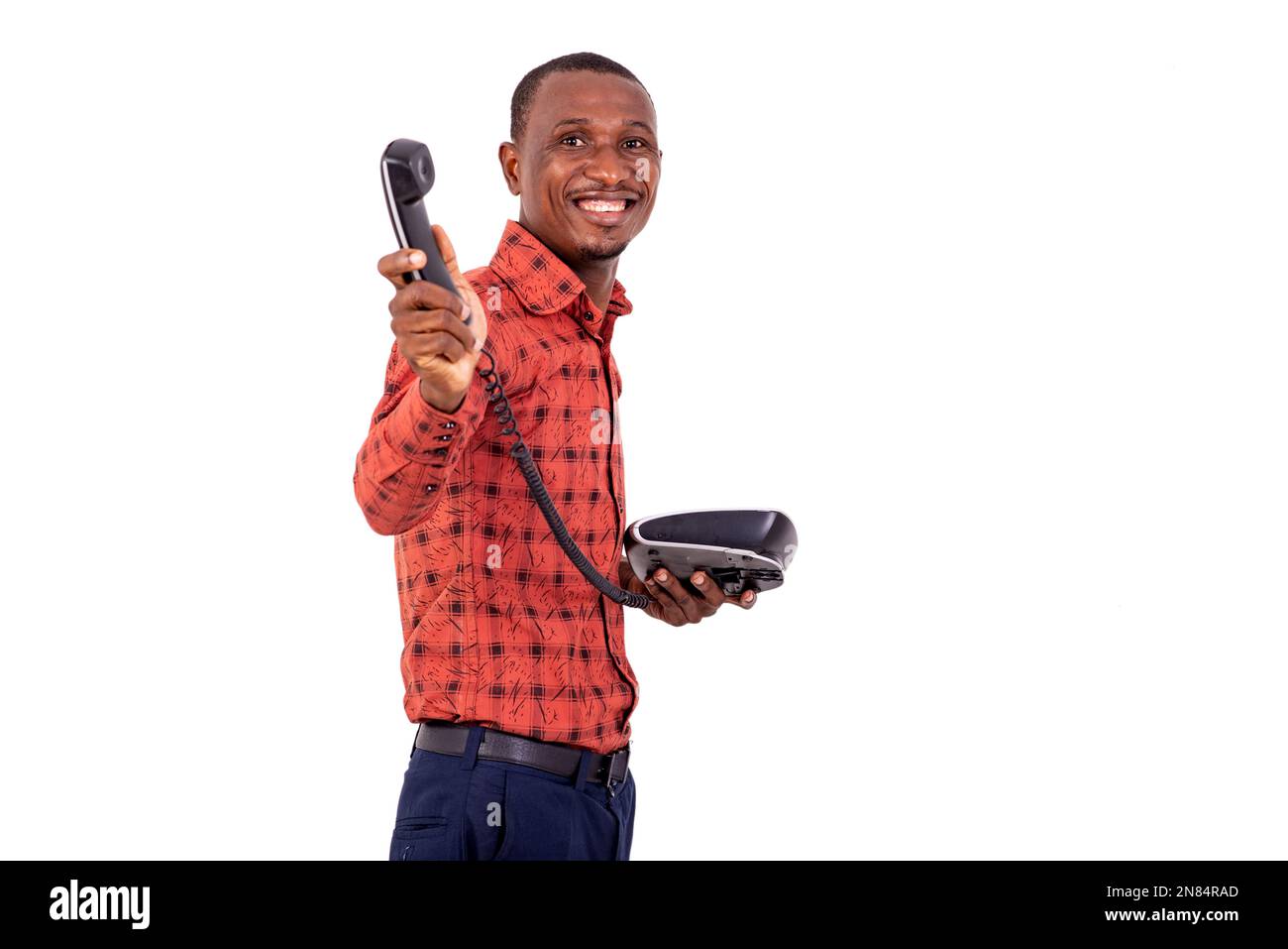 un hombre de negocios guapo en camisa a cuadros de pie sobre fondo blanco que muestra el teléfono, riendo. Foto de stock