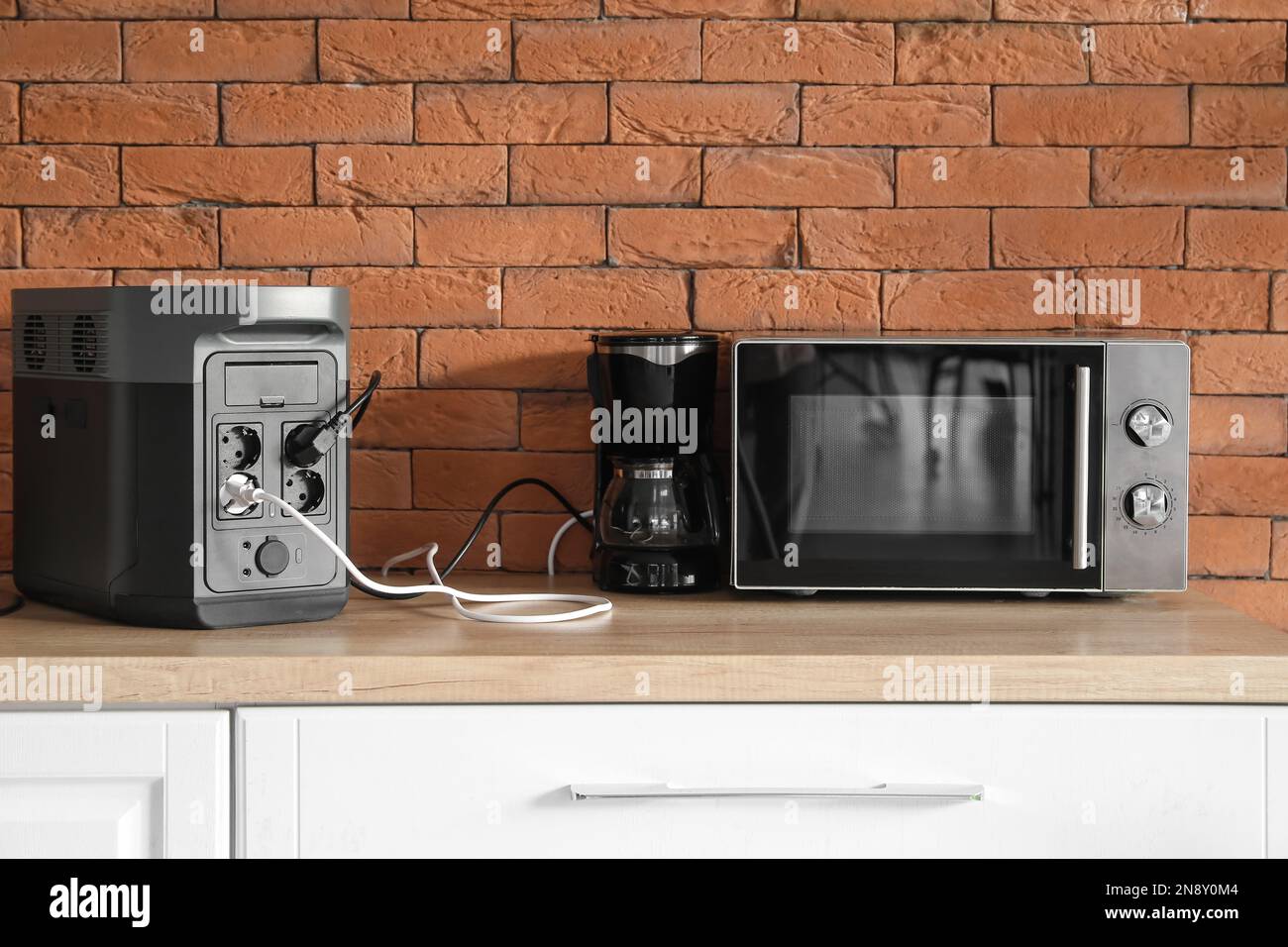 Máquina de café y horno de microondas enchufado en la central eléctrica  portátil en el mostrador de la cocina Fotografía de stock - Alamy