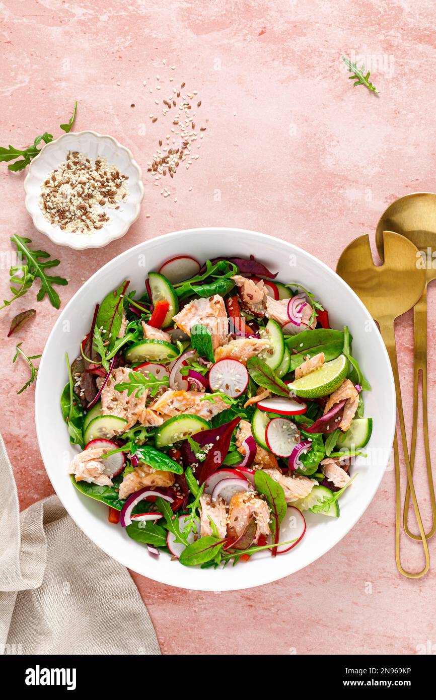 Ensaladera de salmón con rábano fresco, pepino, cebolla roja y verduras de hojas verdes mixtas. Comida de dieta saludable, menú de almuerzo. Vista superior Foto de stock