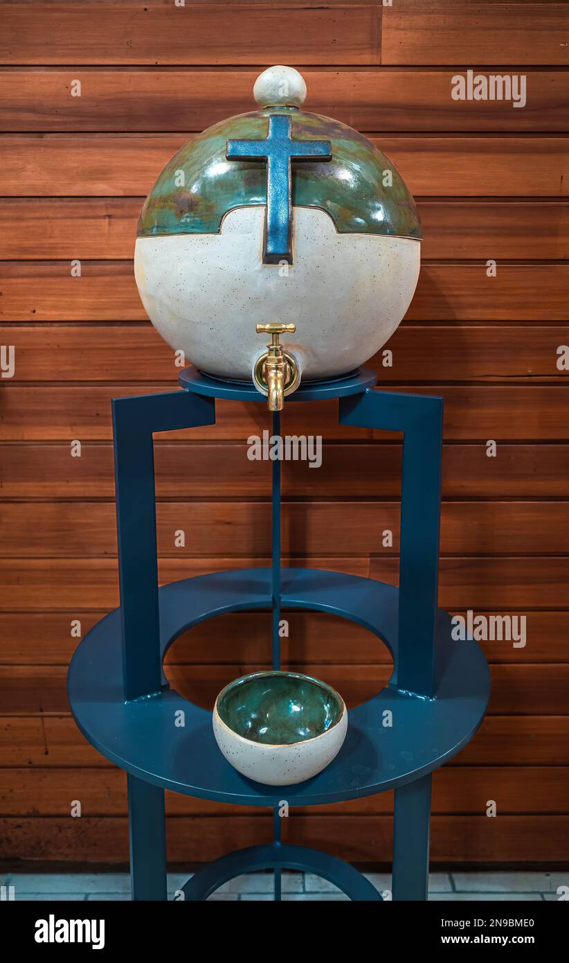 Bremgarten, Suiza - 13 de noviembre de 2022: Un contenedor moderno, artísticamente diseñado para el agua bendita en forma de globo y con una cruz en un azul Foto de stock