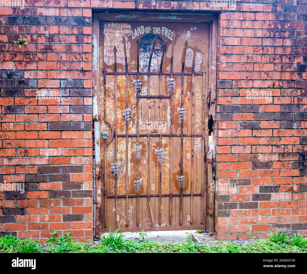 NUEVA ORLEANS, LA, EE.UU. - 2 DE FEBRERO de 2023: Puerta de metal oxidado y puerta de seguridad y una pared de ladrillo y una improvisación artística de un hombre detrás de las rejas Foto de stock