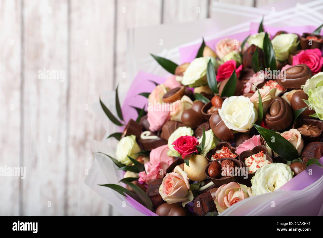 Hermoso ramo de flores y dulces de chocolate sobre fondo de madera blanca,  primer plano. Espacio para texto Fotografía de stock - Alamy