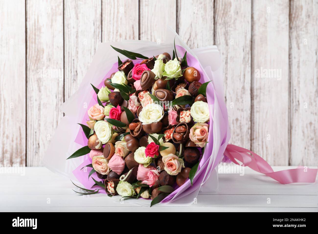 Hermoso ramo de flores y caramelos de chocolate en la mesa de madera blanca  Fotografía de stock - Alamy