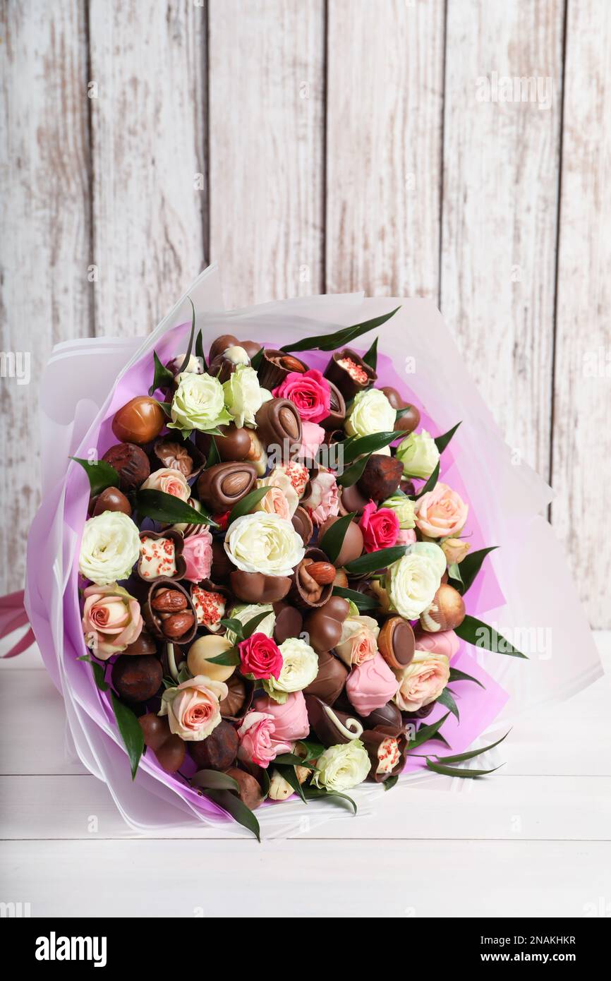 Hermoso ramo de flores y caramelos de chocolate en la mesa de madera blanca  Fotografía de stock - Alamy
