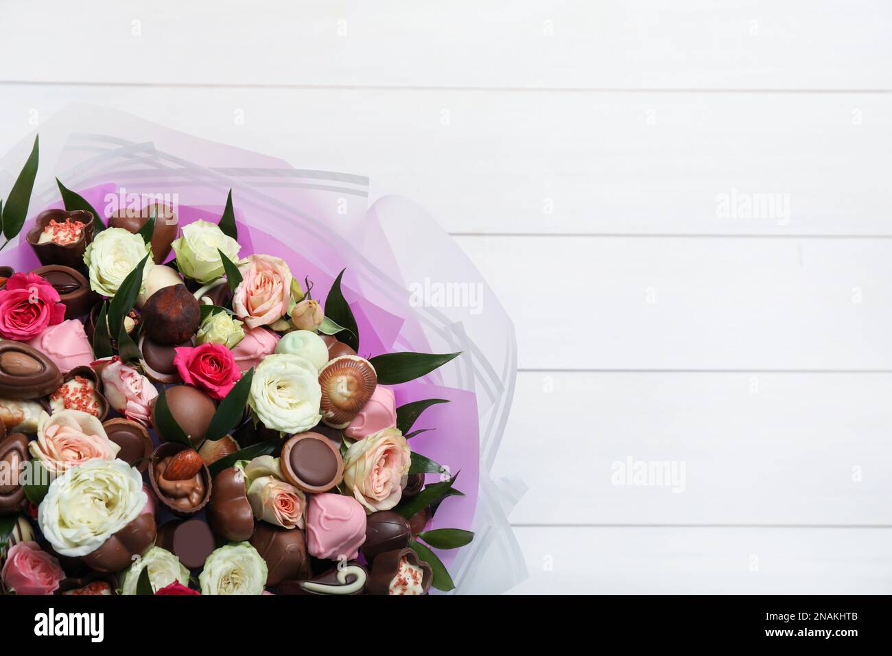 Hermoso ramo de flores y dulces de chocolate sobre fondo de madera blanca,  vista superior. Espacio para texto Fotografía de stock - Alamy