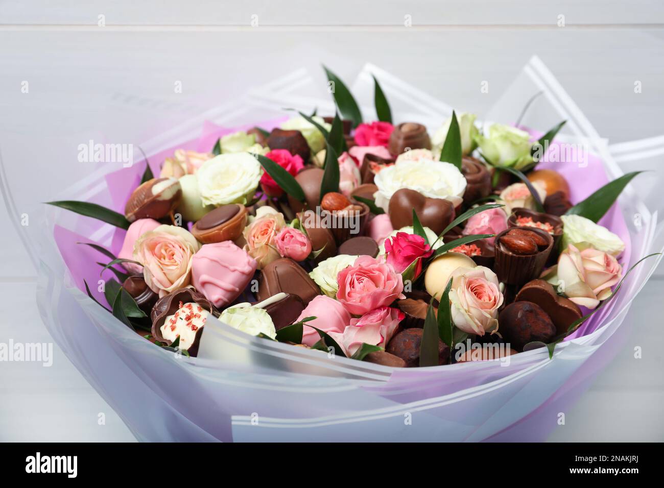 Hermoso ramo de flores y dulces de chocolate sobre fondo claro, primer  plano Fotografía de stock - Alamy