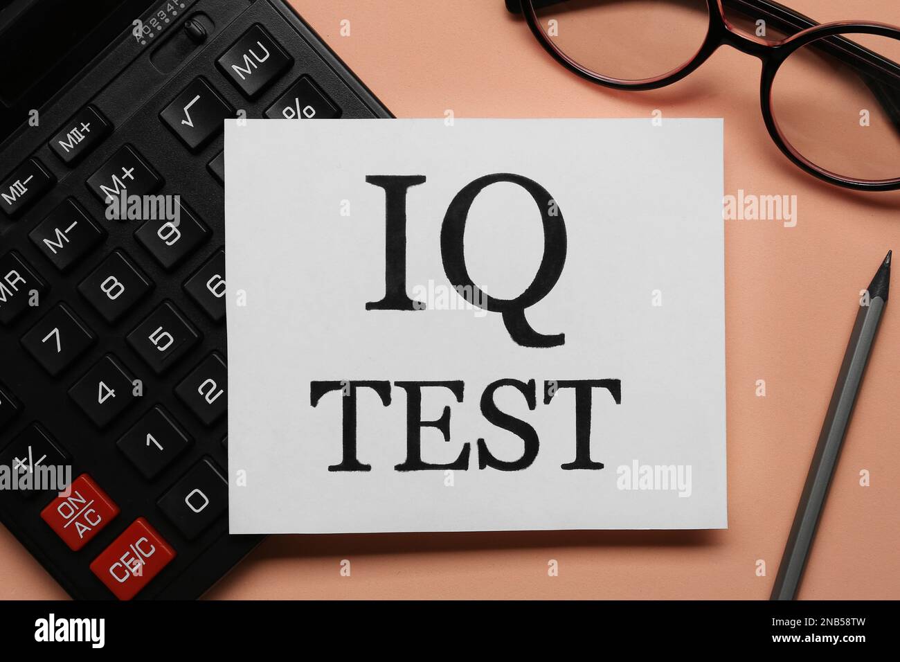 Nota con texto IQ Test, calculadora, gafas y lápiz sobre fondo coral, plano  lay Fotografía de stock - Alamy