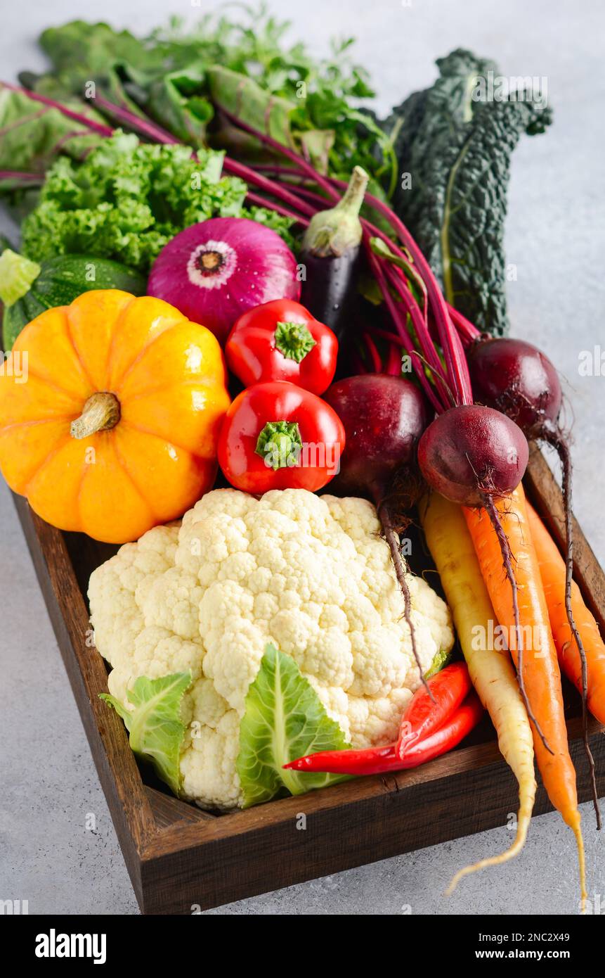 Verduras orgánicas frescas en caja de madera sobre fondo de hormigón gris. Foto de stock