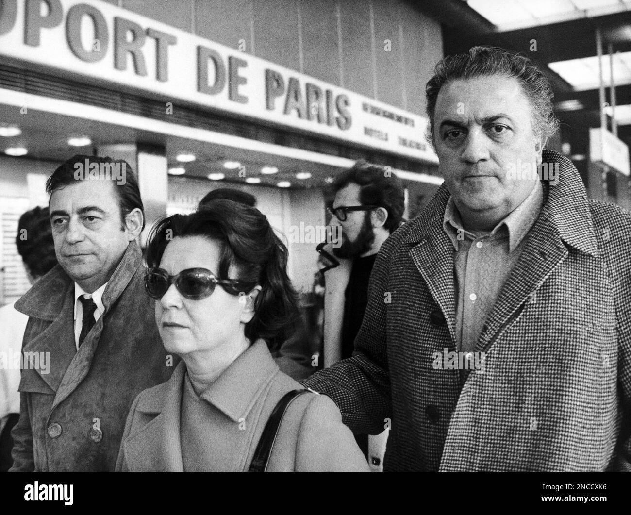 Italian director Federico Fellini, right, arrives at the Paris, France, airport on November 28, 1969, accompanied by his wife, Italian actress Giulietta Masina and French actor Francois Perier, to present his film "Satyricon". (AP Photo/Michel Lipchitz) Foto de stock