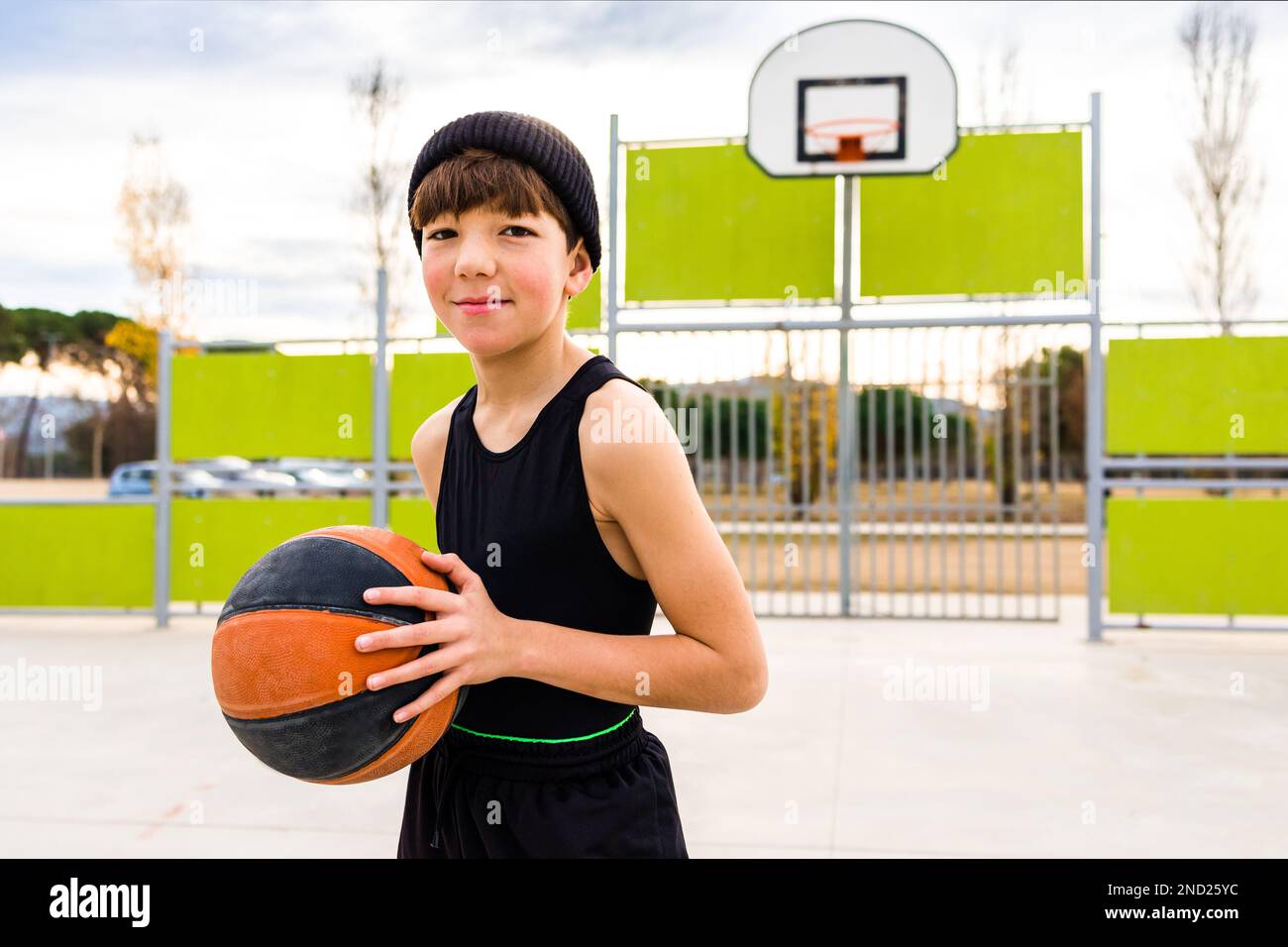 Niño deportivo joven en ropa deportiva y sombrero dribbling bola mientras  practica baloncesto en la cancha contra el aro durante el entrenamiento  Fotografía de stock - Alamy