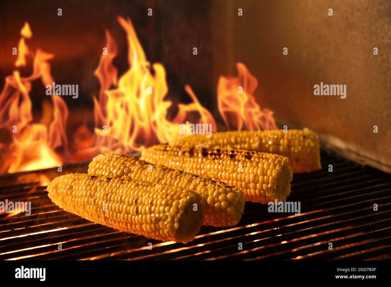 Cocinar deliciosas mazorcas de maíz fresco en la parrilla en el horno con  leña encendida Fotografía de stock - Alamy