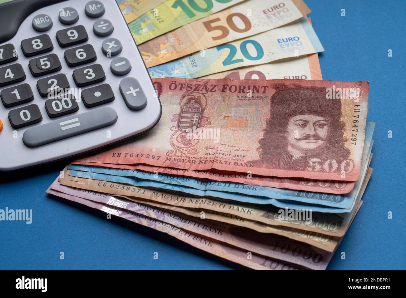 Hay forints húngaros y billetes en euros en una superficie plana. Junto a  él hay una calculadora sobre una mesa azul. Tipo de cambio HUF EUR  Fotografía de stock - Alamy