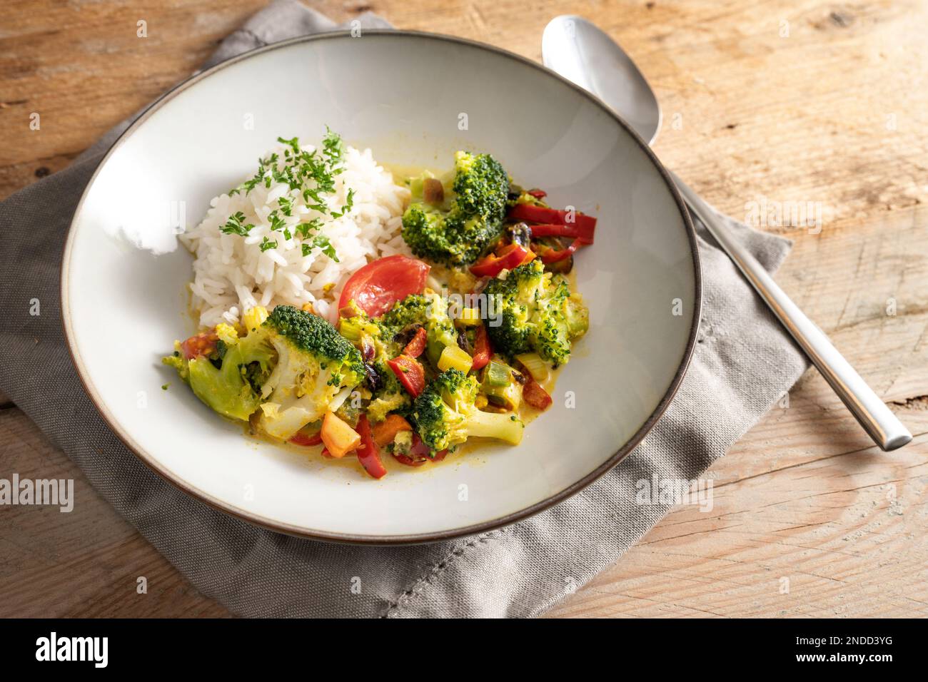 Curry de brócoli vegetariano con arroz y perejil adornan en un plato gris sobre una mesa de madera rústica, plato de verduras caseras saludables, espacio de copia, selecto Foto de stock