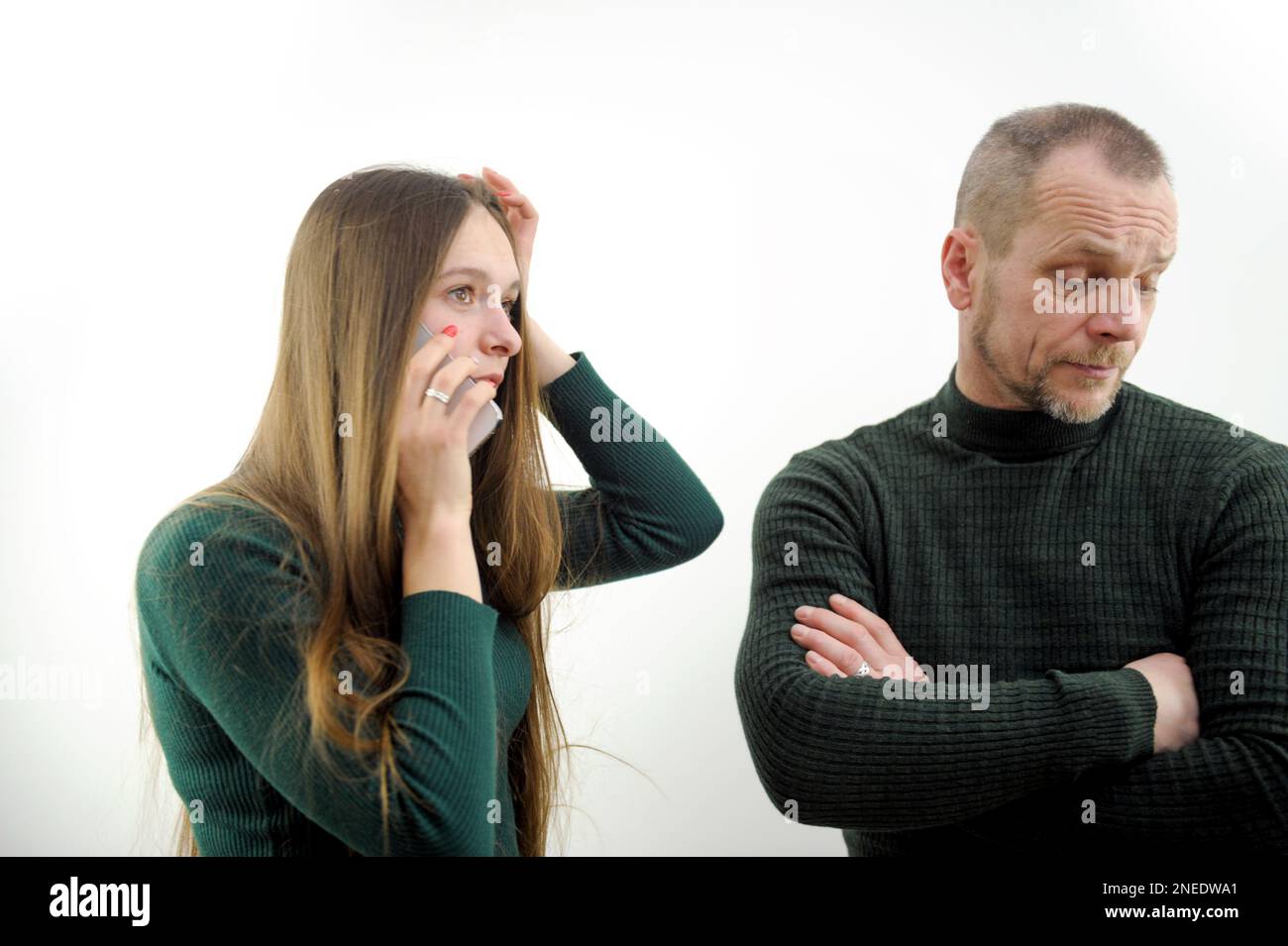 Desconfianza El padre insatisfecho no deja que la hija vaya a la fiesta manos puestas en el pecho chica está hablando por teléfono molesto mirando a distancia hombre se apartó frunciendo el ceño y el bigote de la frente barba Foto de stock