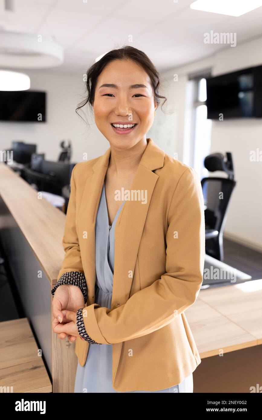 Imagen vertical de empresaria asiática feliz mirando a la cámara en la oficina Foto de stock