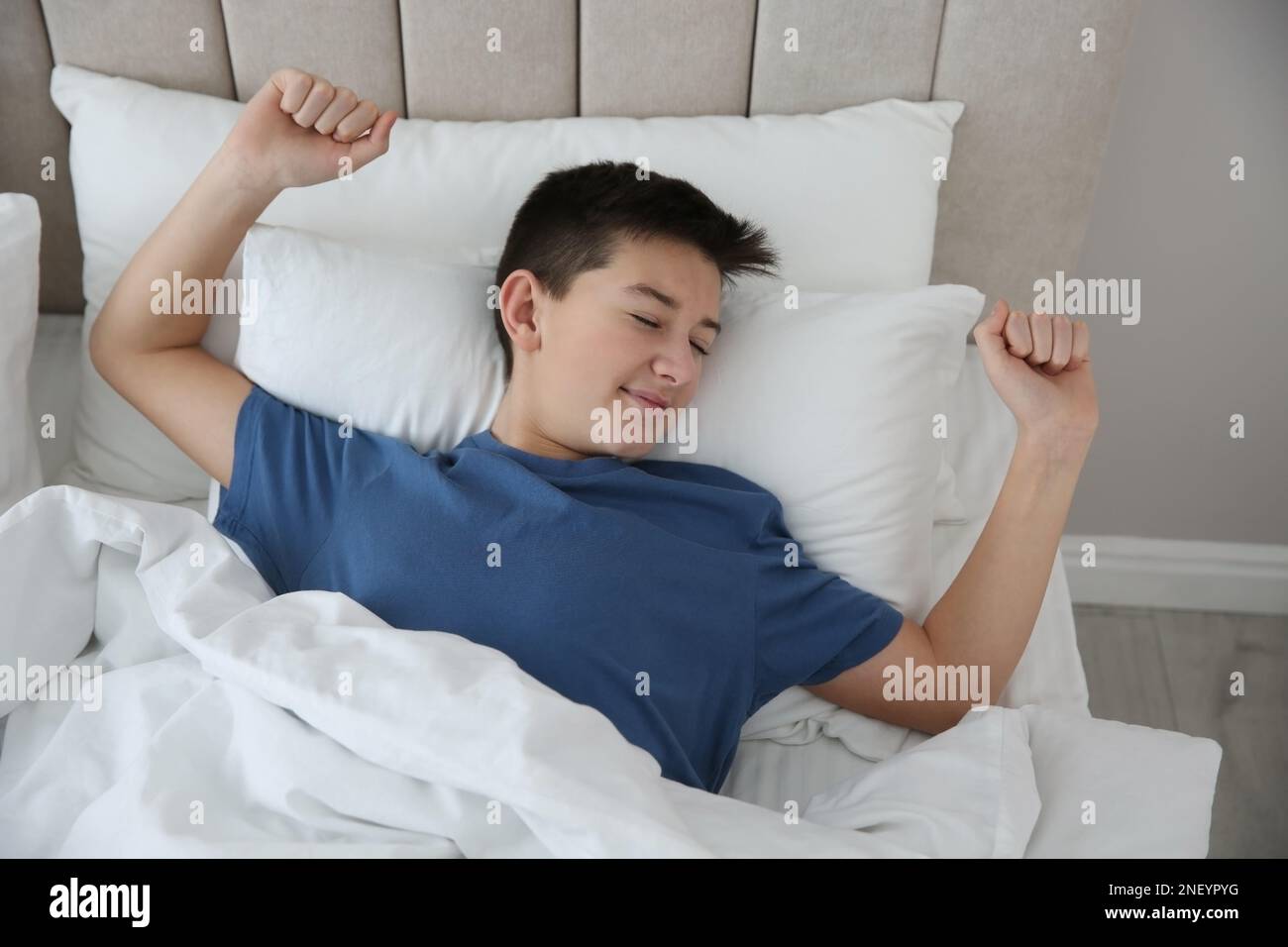 Retrato de mujer relajado placer estiramiento en la cama en el dormitorio  con ropa de cama limpia y blanca mirando el reloj despertador en la mesilla  de noche Fotografía de stock 