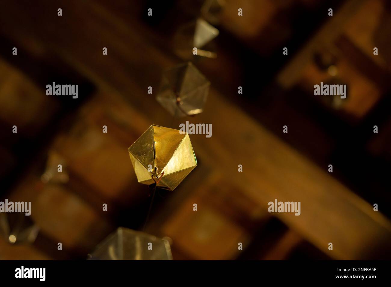 Detalle de ángulo bajo de un diamante dorado que cuelga del techo de madera  del porche granollers seguido de dos más por encima de él Fotografía de  stock - Alamy