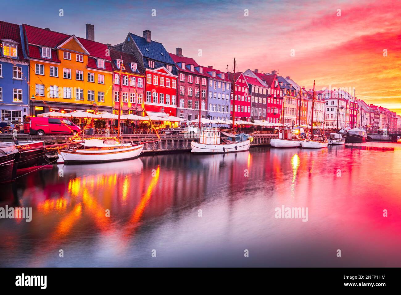 Copenhague, Dinamarca. Experimente la impresionante belleza del canal Nyhavn al amanecer, con sus icónicos edificios coloridos y sus serenos reflejos del agua. Foto de stock