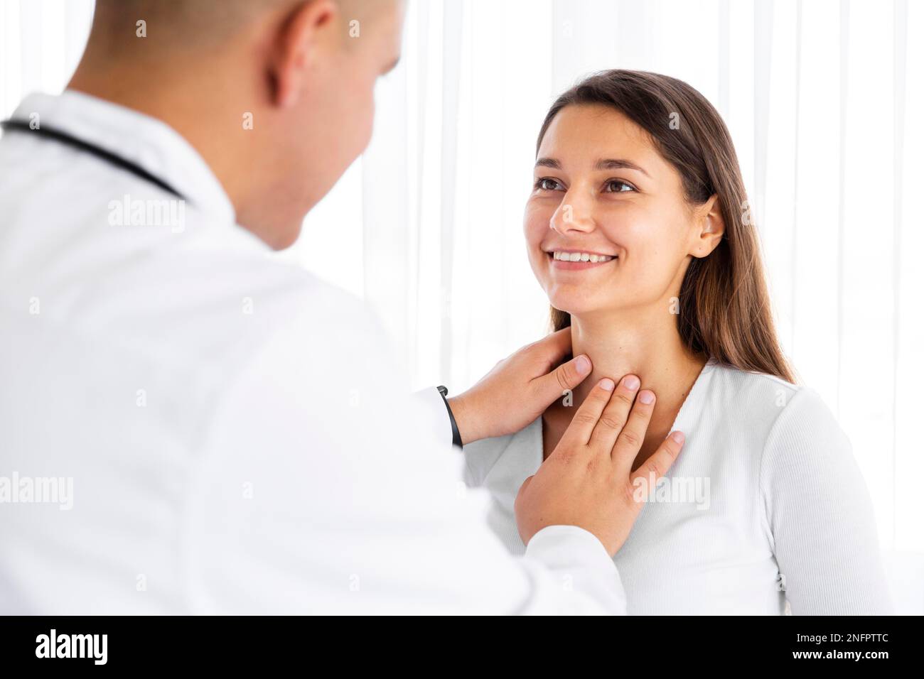 Vista posterior Doctor examinando el cuello de la mujer Foto de stock