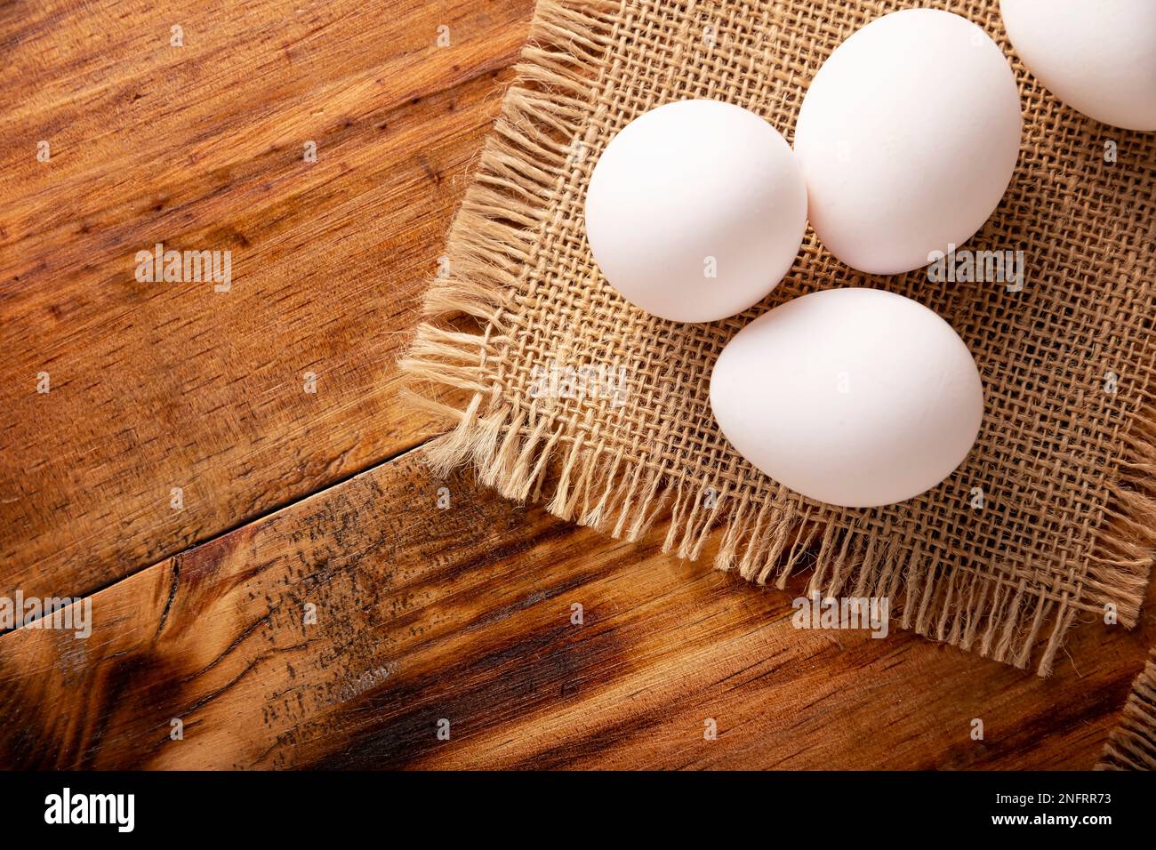 Muchos huevos de pollo blanco en la mesa de madera rústica. Producto alimenticio nutritivo y económico muy popular. Vista superior de tabla con espacio de copia Foto de stock