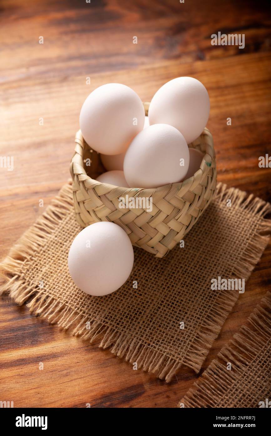 Muchos huevos de pollo blanco en la mesa de madera rústica. Producto alimenticio nutritivo y económico muy popular. Foto de stock
