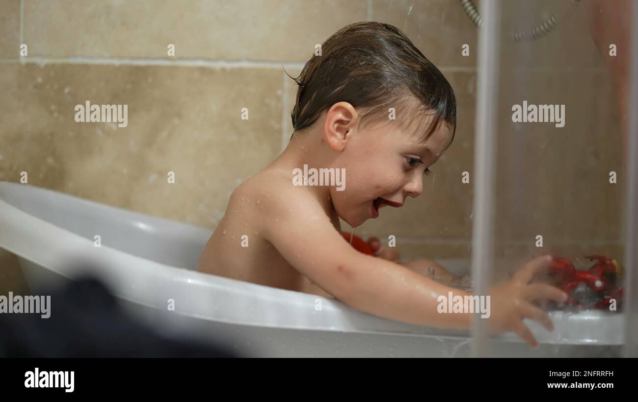 Un niño feliz bañándose dentro de una pequeña bañera. Bebé niño pequeño  baño rutina jugando con el juguete. Estilo de vida infantil Fotografía de  stock - Alamy