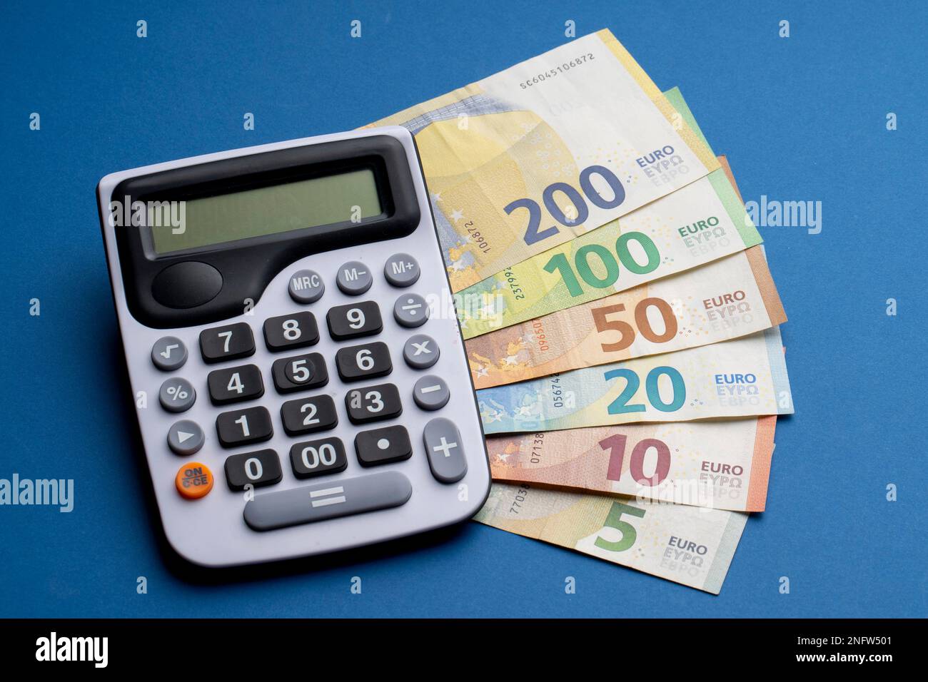 Hay billetes en euros en una superficie plana. Junto a él hay una  calculadora sobre una mesa azul. Cálculo del tipo de cambio bancario  Fotografía de stock - Alamy