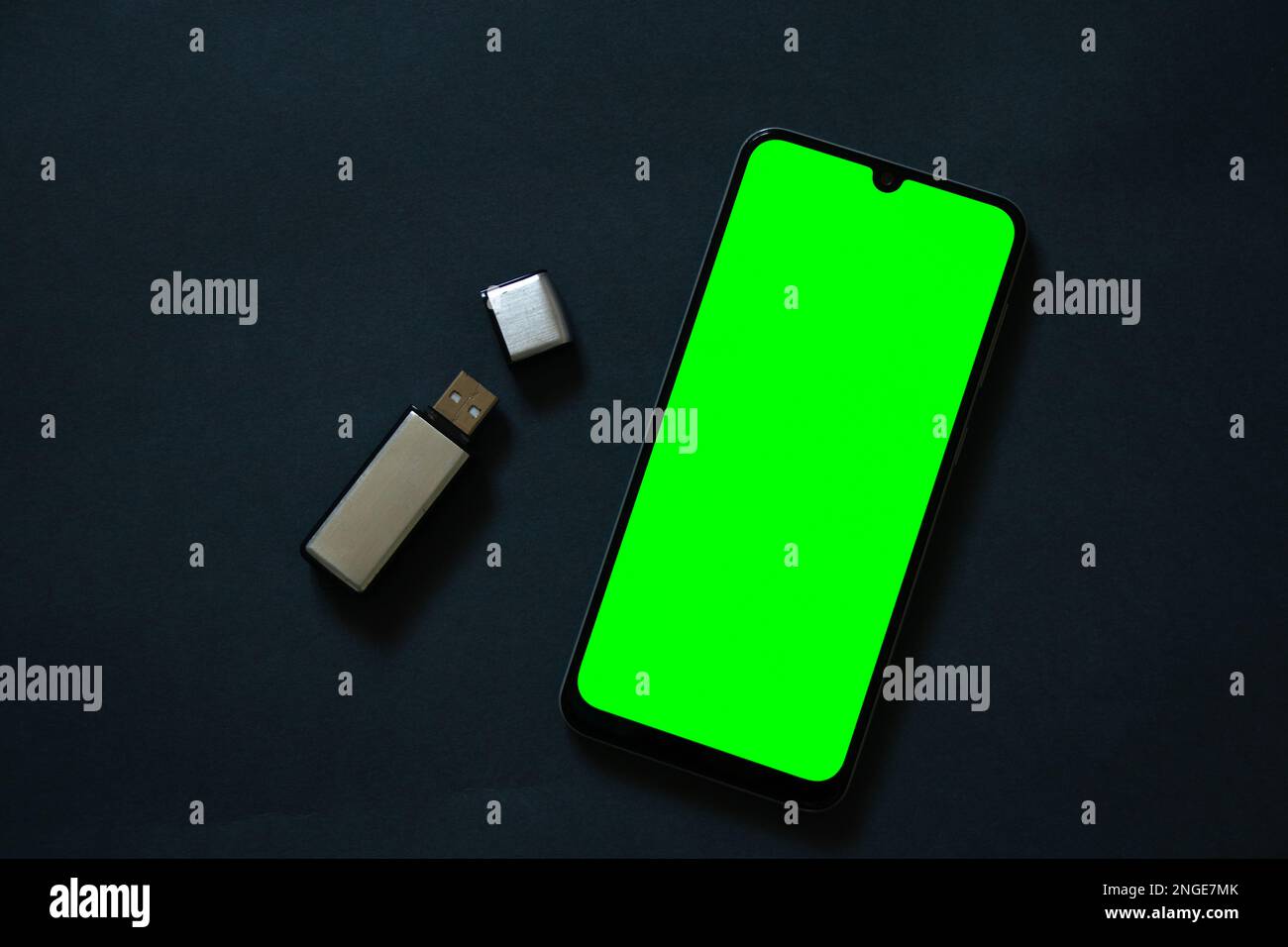 La unidad USB se encuentra y el teléfono con pantalla táctil con una  pantalla verde sobre un fondo oscuro Fotografía de stock - Alamy