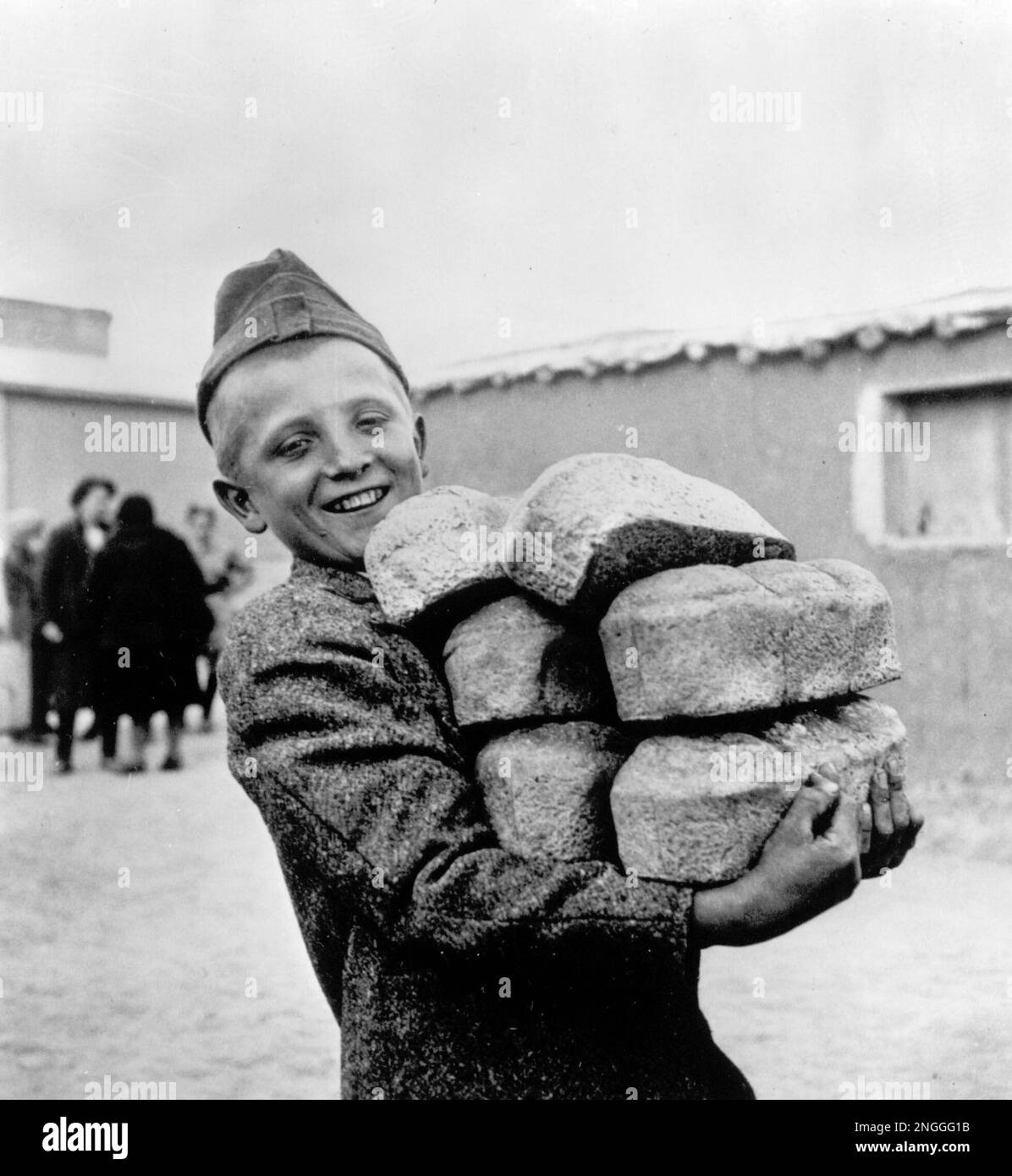 A Polish boy has his arms loaded down with six loafs of bread, made