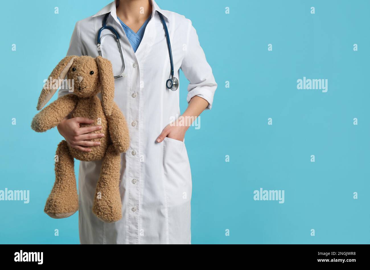 Pediatra con conejito de juguete y estetoscopio sobre fondo turquesa,  primer plano. Espacio para texto Fotografía de stock - Alamy