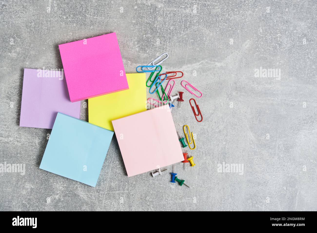 Paquetes de pegatinas de papel para escribir notas y clips de papel con  botones de papelería de fondo de hormigón gris Fotografía de stock - Alamy