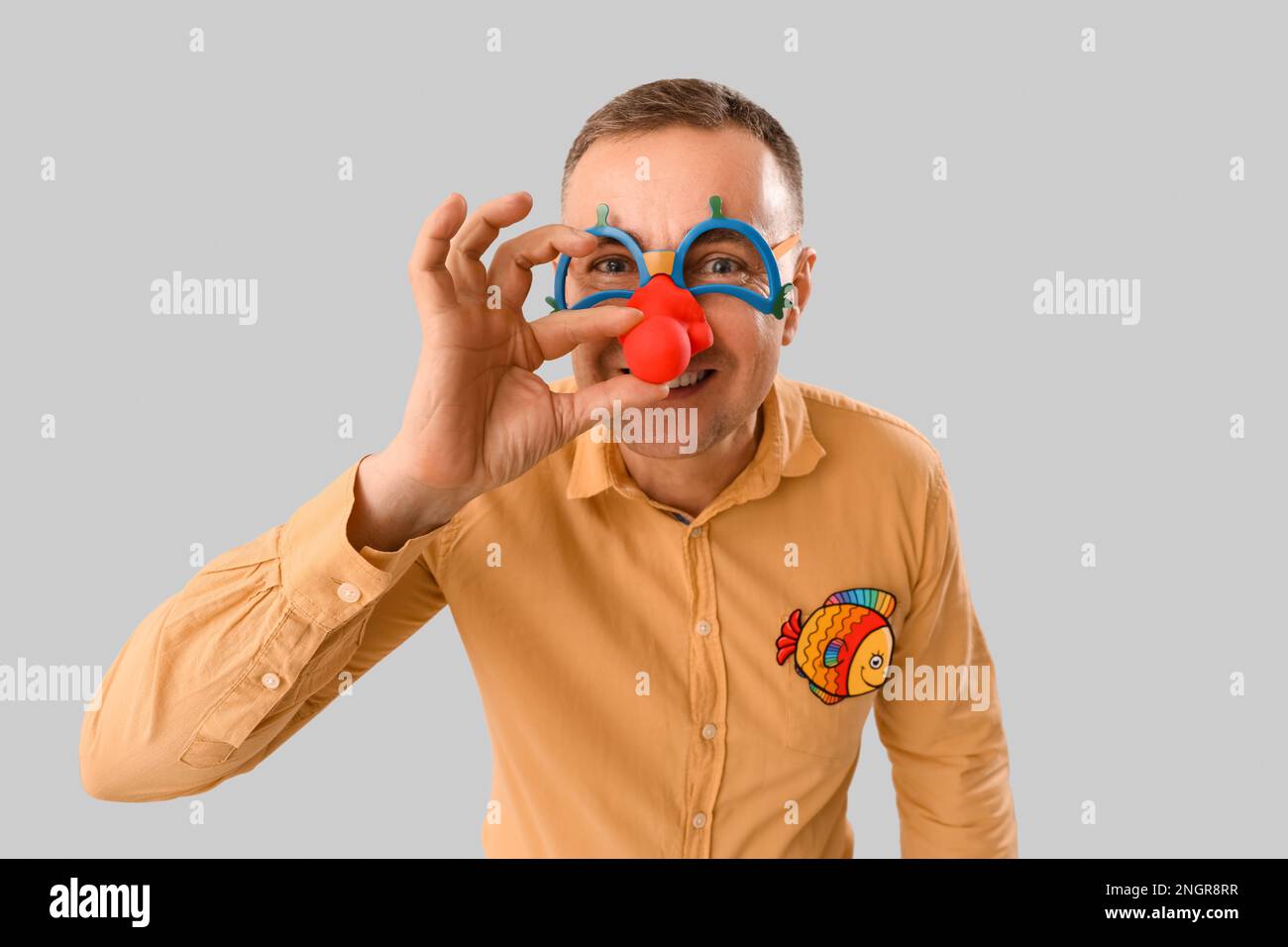 Hombre maduro en disfraz divertido sobre fondo gris, closeup. Celebración  del Día de los Inocentes de Abril Fotografía de stock - Alamy
