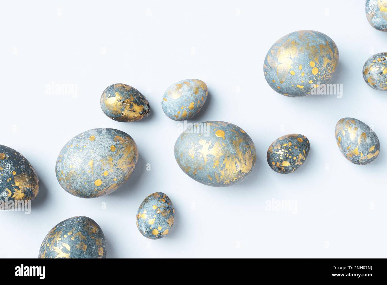Huevos de Pascua azules con manchas doradas sobre fondo azul claro de Pascua. Tarjeta de felicitación de Pascua chic, flat lay, composición diagonal. Foto de stock