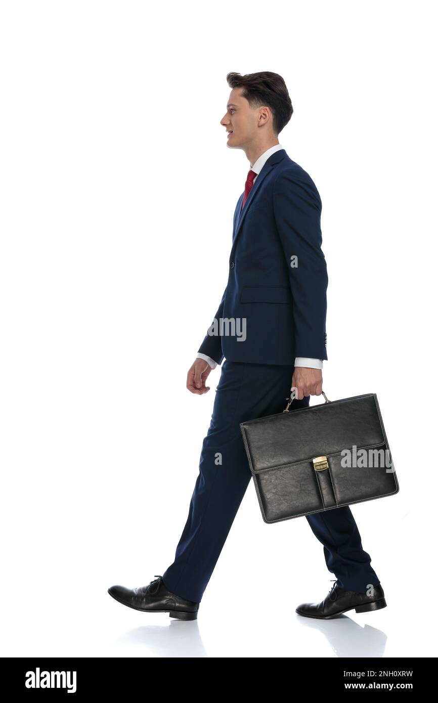 empresario atractivo caminando y sosteniendo un maletín, usando un traje y  corbata contra el fondo blanco Fotografía de stock - Alamy