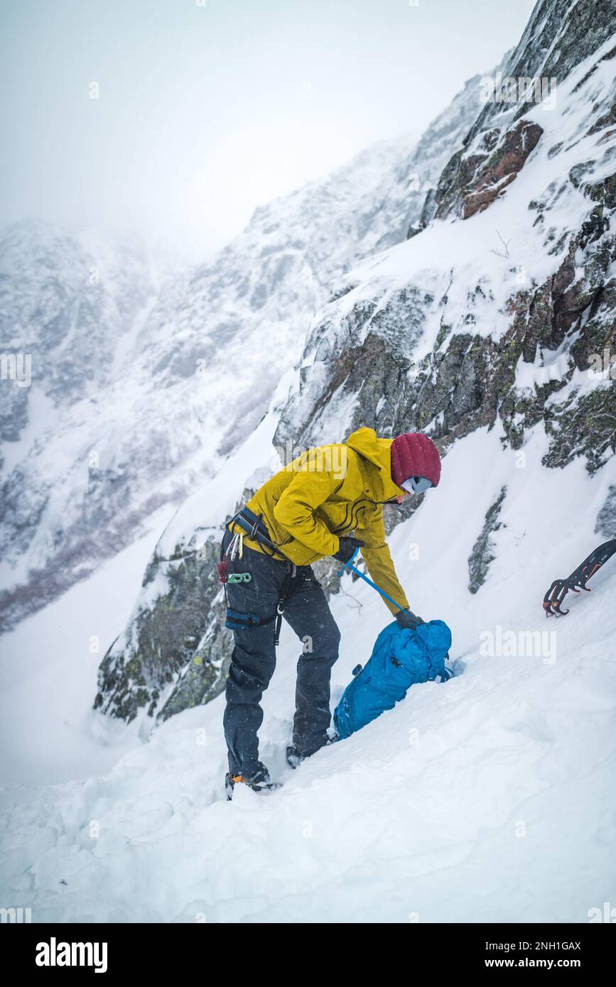 Hombre que se prepara para escalar el hielo rodeado de paisaje nevado Foto de stock