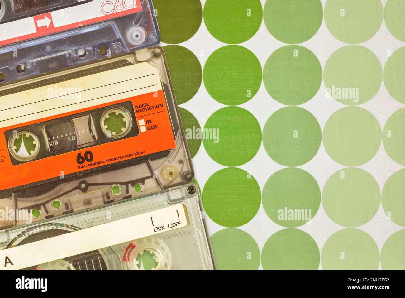 Tres coloridos casetes compactos de audio vintage frente a los fondos de pantalla retro de los años setenta Foto de stock