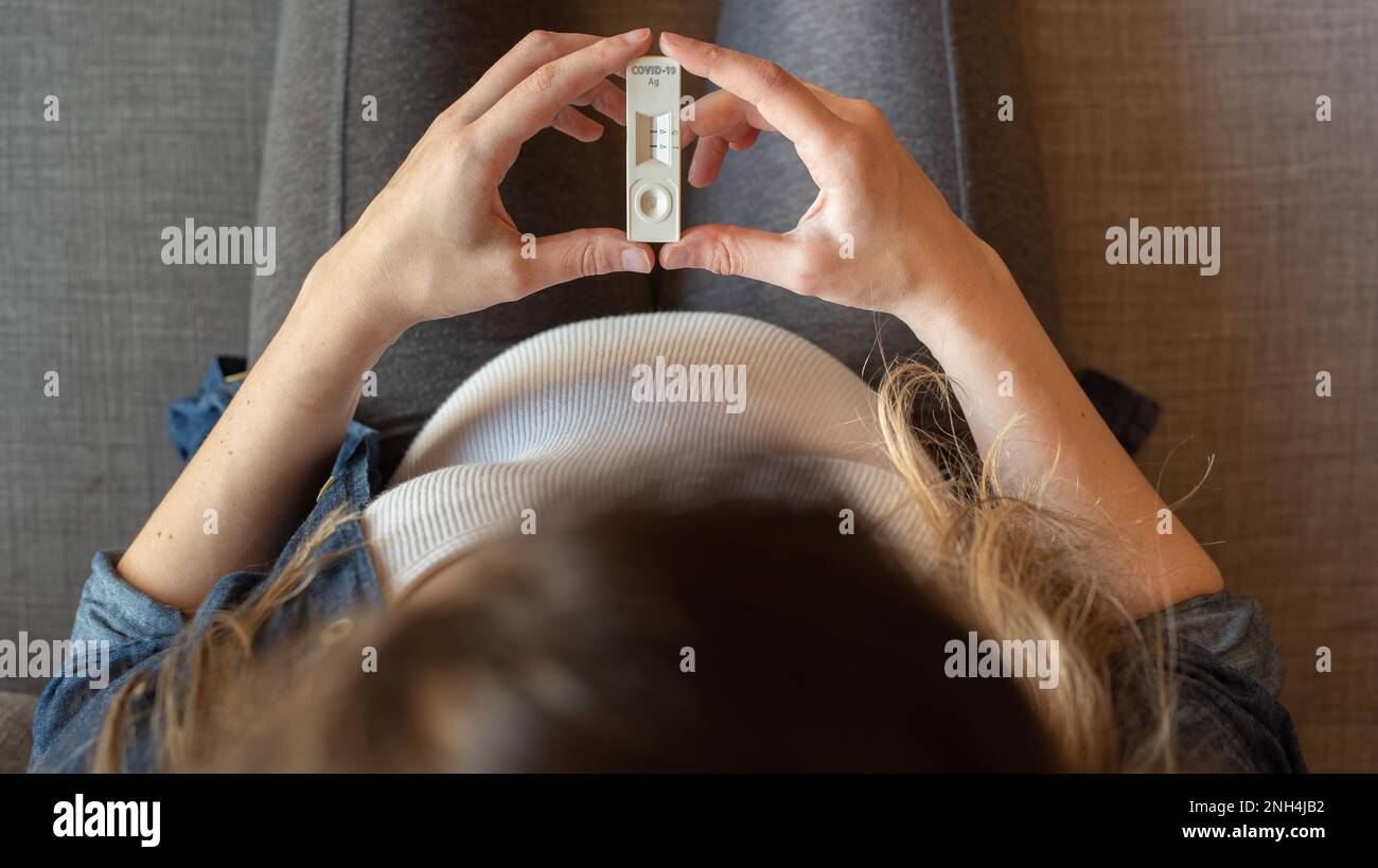 Vista superior de una mujer embarazada con resultado positivo de la prueba mediante el uso de un dispositivo de prueba rápida para COVID-19 Foto de stock