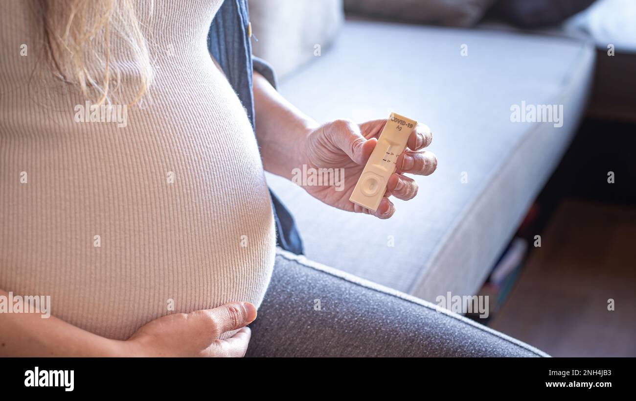 Mujer embarazada con resultado positivo de la prueba mediante el uso de dispositivo de prueba rápida para COVID-19 Foto de stock