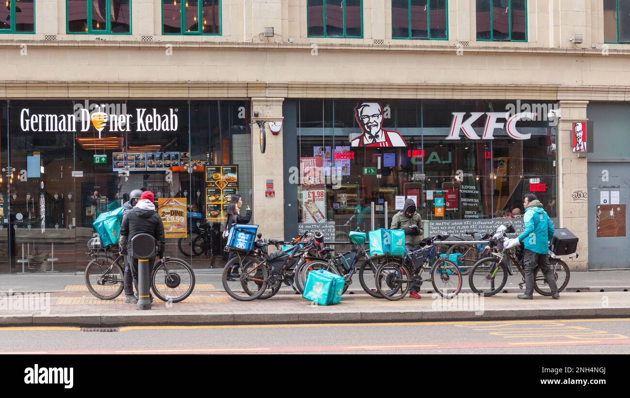Deliveroo riders con bicicletas esperando fuera de Food Outlets en Manchester Reino Unido Foto de stock