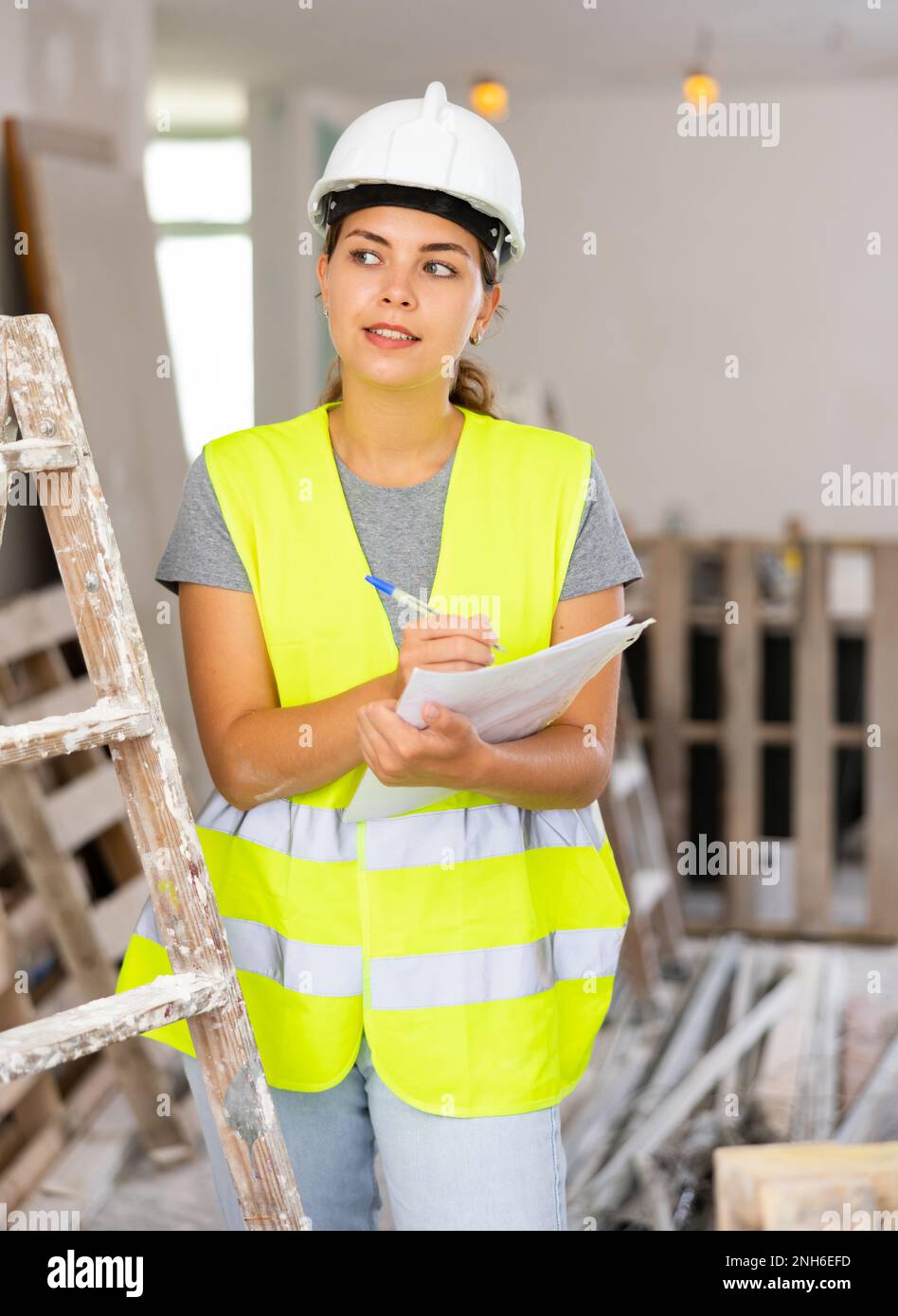 Mujer capataz en un casco protector y amarillo comprueba trabajo de construcción completado en el dibujo Fotografía de stock - Alamy