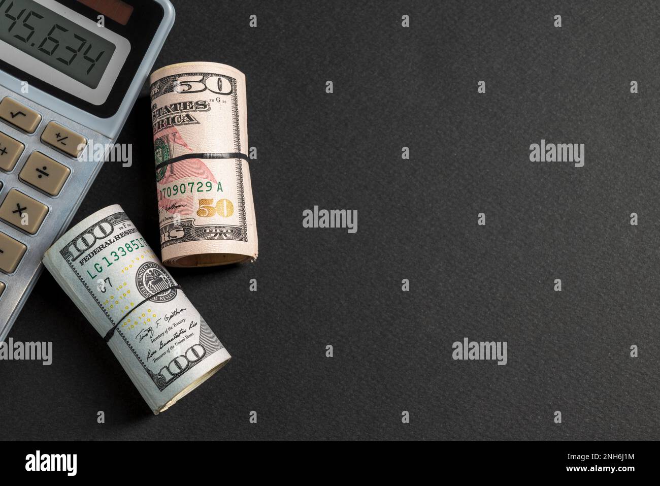 Rollos de 50 y 100 dólares de EE.UU. De pie cerca de la calculadora sobre  fondo oscuro Fotografía de stock - Alamy