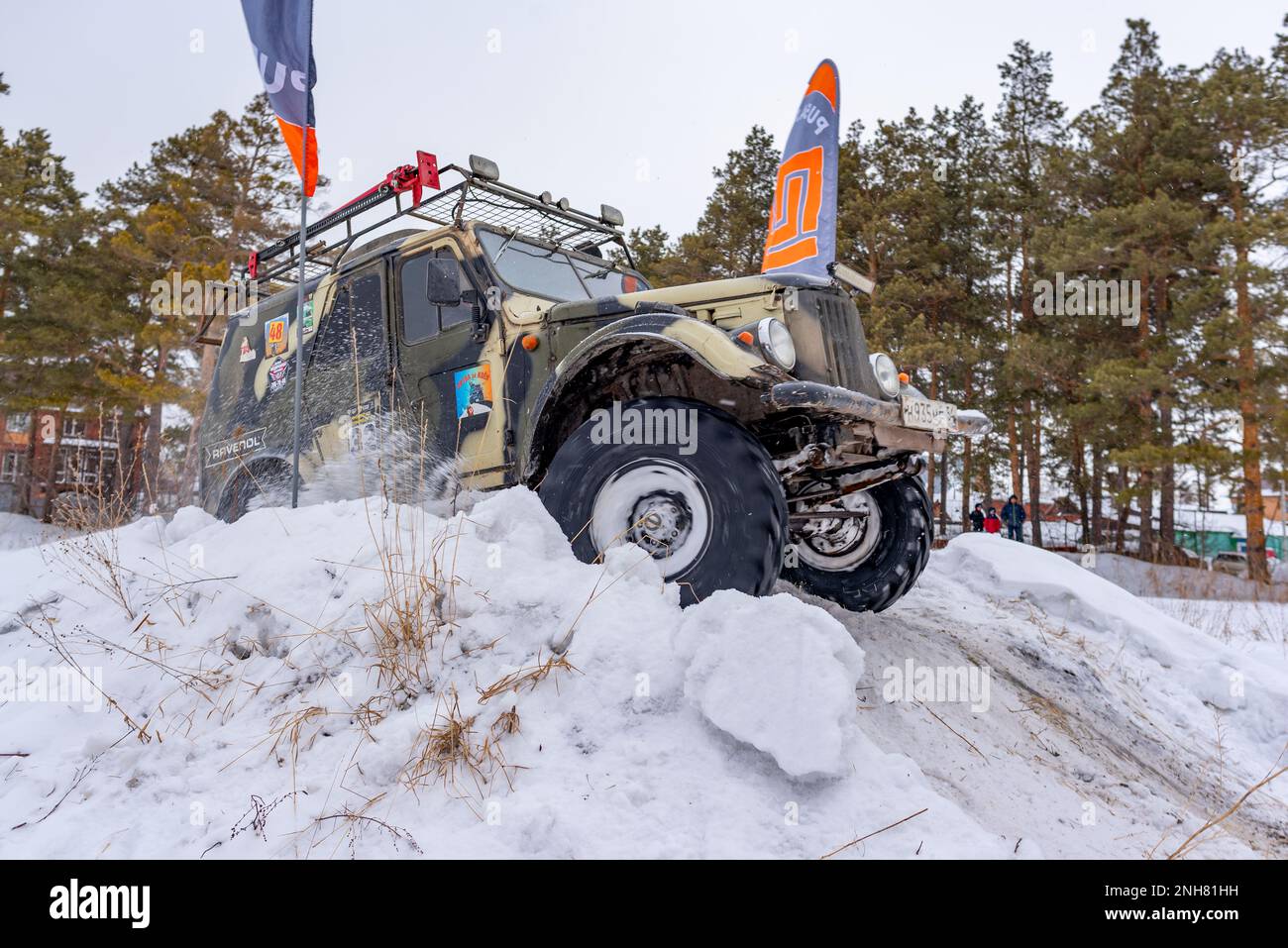 El viejo SUV todoterreno ruso 'gaz69 4x4' va rápidamente levantando nieve en invierno en una colina con banderas de la meta. Foto de stock