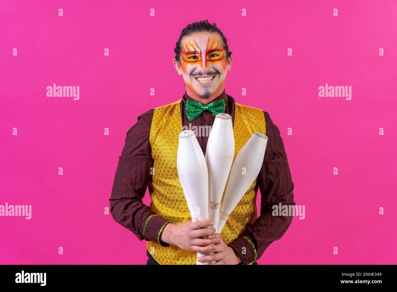 Malabarista en un chaleco y con la cara pintada malabares sobre un fondo  rosa Fotografía de stock - Alamy